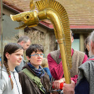 Museumsbesucher betrachten einen großen goldenen Stab mit drachenförmigem Kopf, der hochgehalten wird.