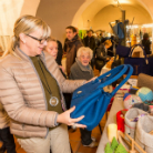 Belebter Markt im Franziskanermuseum: Besucherinnen und Besucher schauen an Ständen vorbei; vorn eine Frau hält und begutachtet eine blaue Stofftasche.