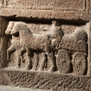Steinrelief eines Fuhrwerks mit zwei Pferden, beladenem Wagen und einem stehenden Kutscher