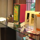 Vitrine mit bunten Buch- und Papierobjekten: aufgestellte Leporellos, Faltbücher und Papieraufsteller in Rot, Grün und Weiß auf Glasboden ausgestellt im Franziskanermuseum