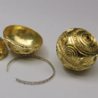 Goldene, reich verzierte Kugel mit abnehmbarem Deckel; daneben ein kleines goldenes Innenbecherchen und eine feine Kette.