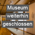 Blick in ein leeres Ausstellungszimmer des Franziskanermuseums mit Vitrinen und Wandtafeln, darüber auffällige Texttafel Museum weiterhin geschlossen.