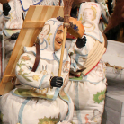 Zwei bemalte Holzfiguren in mittelalterlicher Rüstung und Helmen, kniend nebeneinander, mit Schilden und einem Schwert; detailreiche Bemalung und florale Dekore, vermutlich Teil einer religiösen oder historischen Darstellung